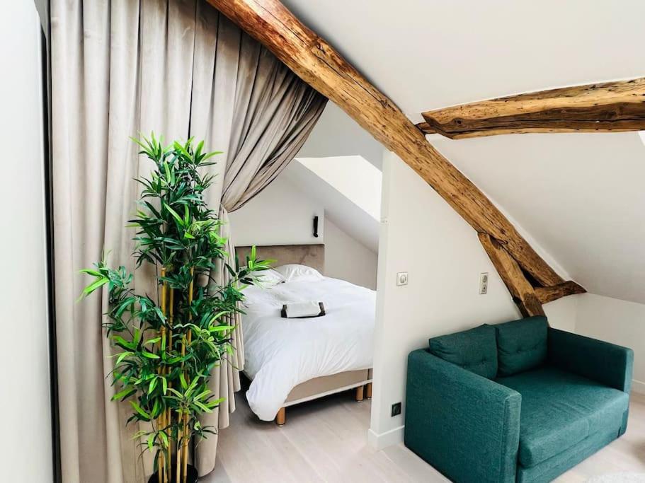 - une chambre avec un lit et une chaise verte dans l'établissement Le StayParis - Charmant logement au cœur du Marais, à Paris