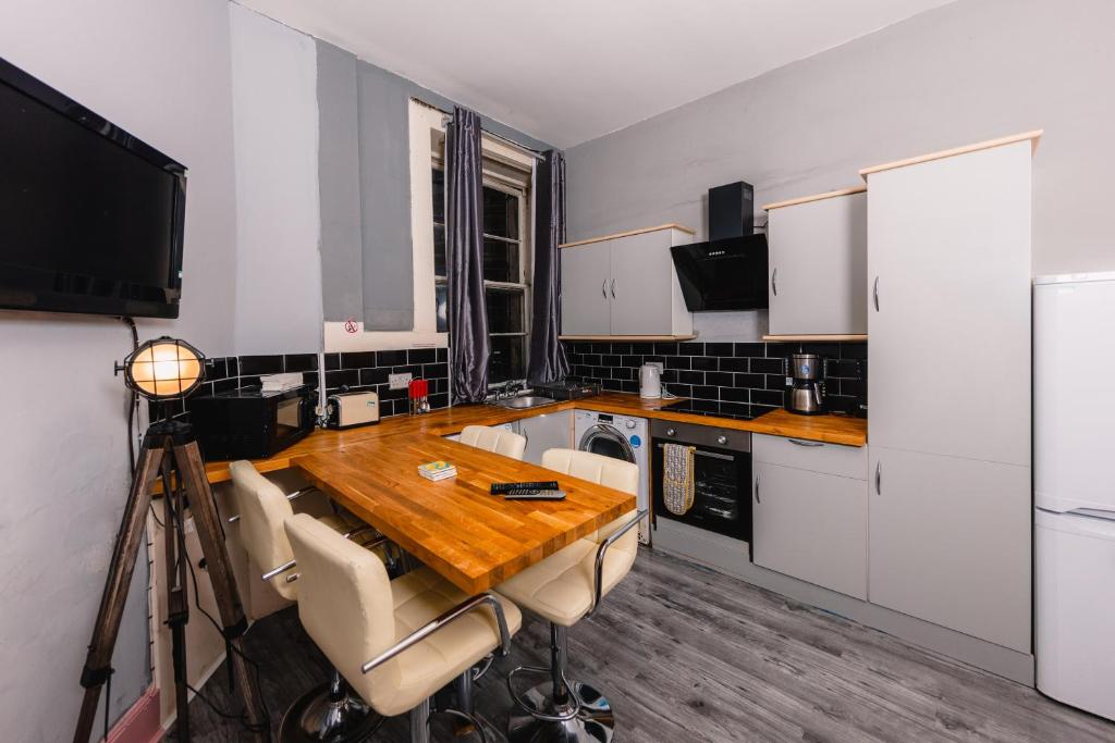 een keuken met een houten tafel met stoelen en een televisie bij Super Central 4 Bedrooms Apartment by Calton Hill in Edinburgh