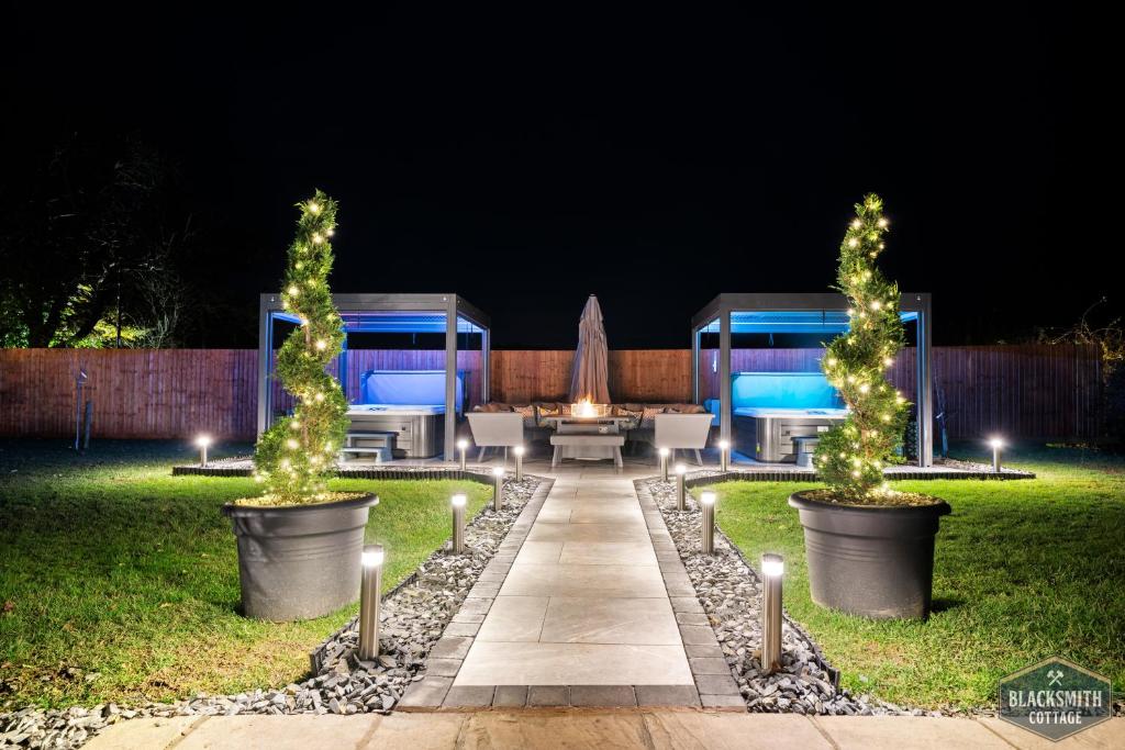 a garden at night with two trees and lights at Luxury cottage, 13 guests with 2 hot tubs in Hoar Cross, Staffs in Newborough