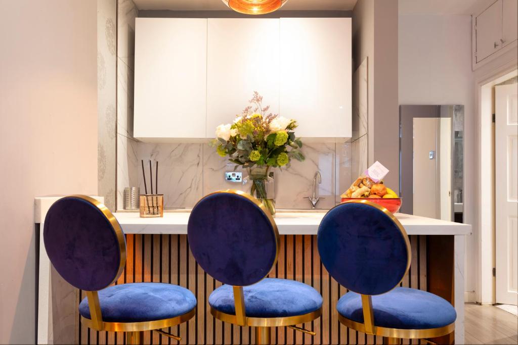 two blue chairs sitting in front of a kitchen counter at THE PAD at Sloane Square in London