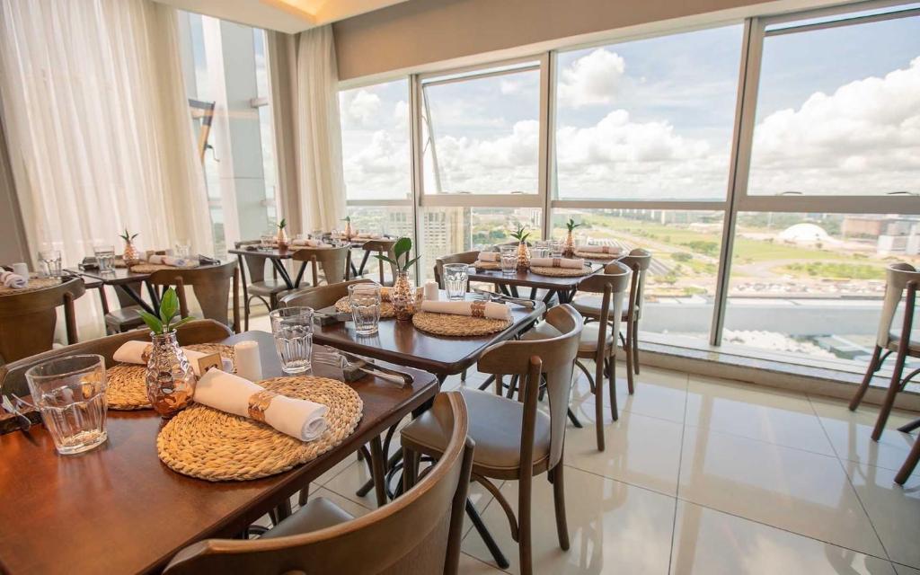 um restaurante com mesas e cadeiras e janelas grandes em F1104 Flat de ótima localização e fácil acesso em Brasília