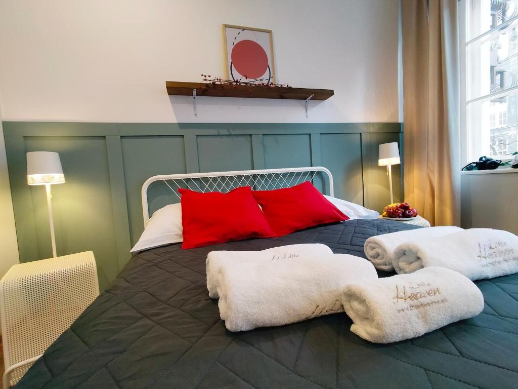a bed with red pillows and towels on it at Długa by Little Heaven in Gdańsk