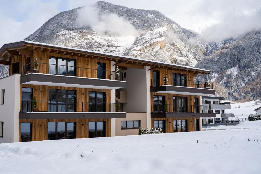 a building in the snow in front of a mountain at Apart Dorhoam in Umhausen