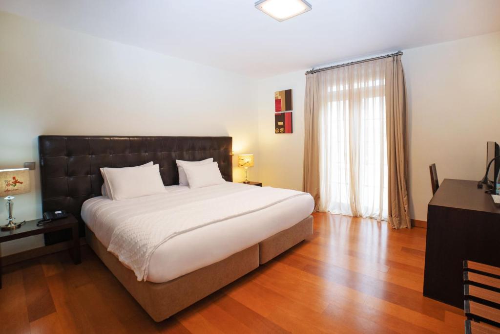 a bedroom with a large white bed and a window at Eirado Hotel in Caldelas