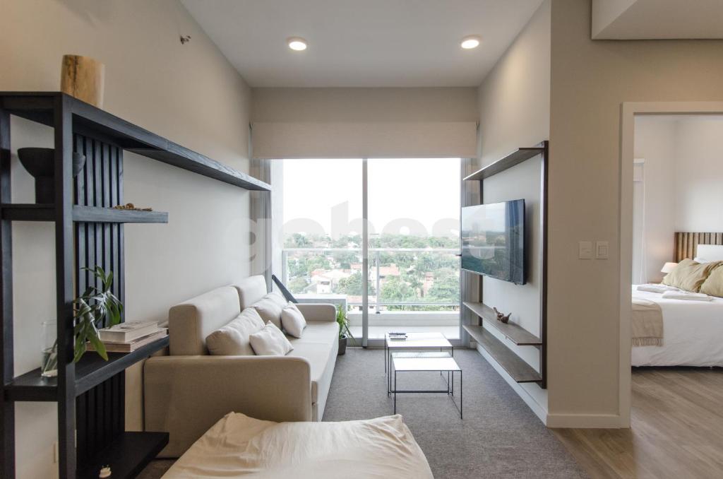 a living room with a couch and a bed and a tv at Brand New Apartment In Las Lomas Neighborhood in Asunción