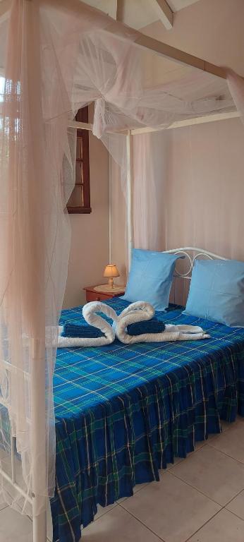 a bedroom with a bed with blue and white sheets at Bienvenue à la ferme ! in Le Moule