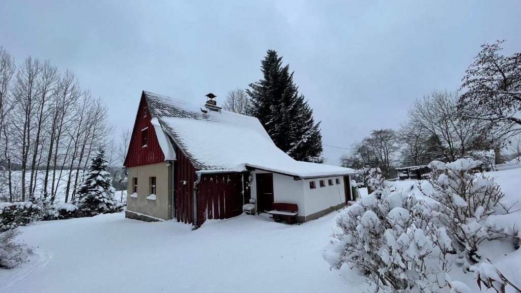 un granero rojo con nieve en el techo en Chalupa Lučany, en Lučany nad Nisou