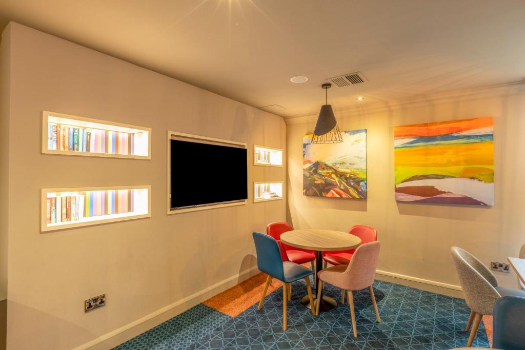 a room with a table and chairs and a tv at Holiday Inn - Glasgow Airport by IHG in Paisley
