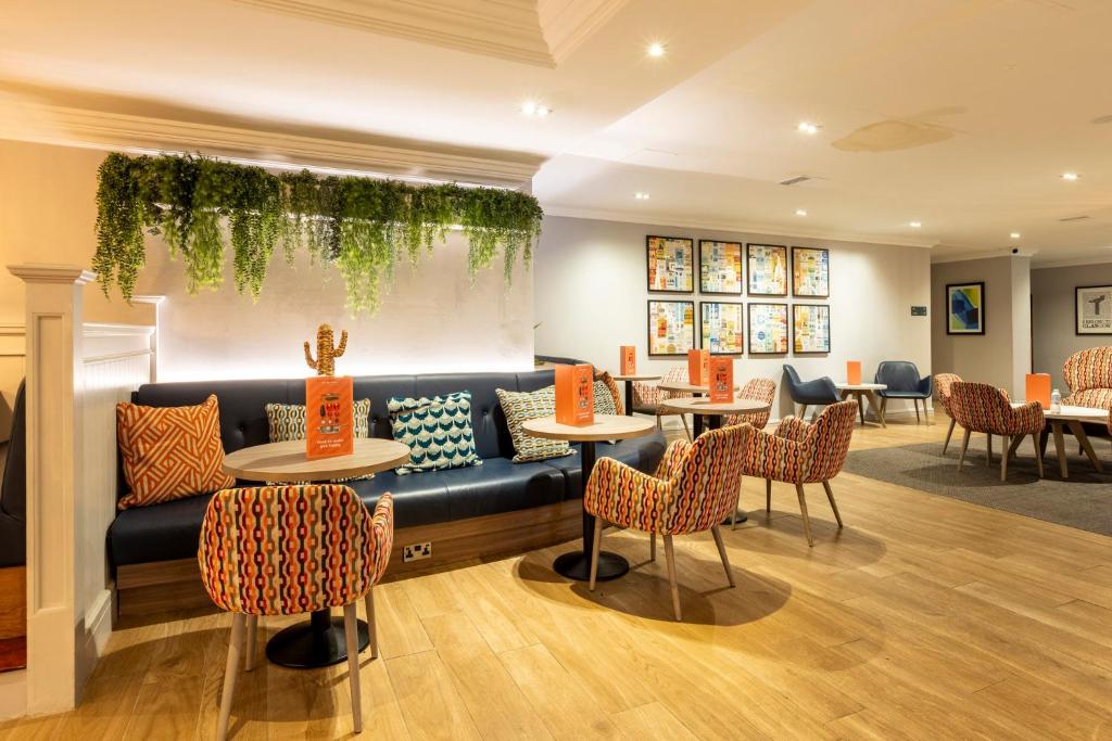 a restaurant with a couch and tables and chairs at Holiday Inn - Glasgow Airport by IHG in Paisley