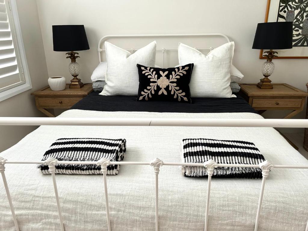 two pictures of a bed with pillows on it at Avalon Beach Cottage- The Islander in Avalon