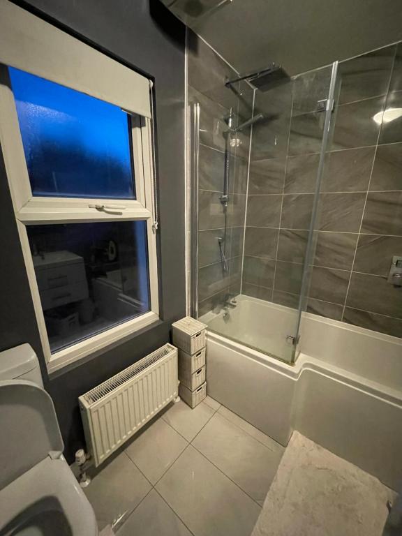 a bathroom with a shower and a toilet and a window at Single Room in Potters Bar Hertfordshire in Potters Bar