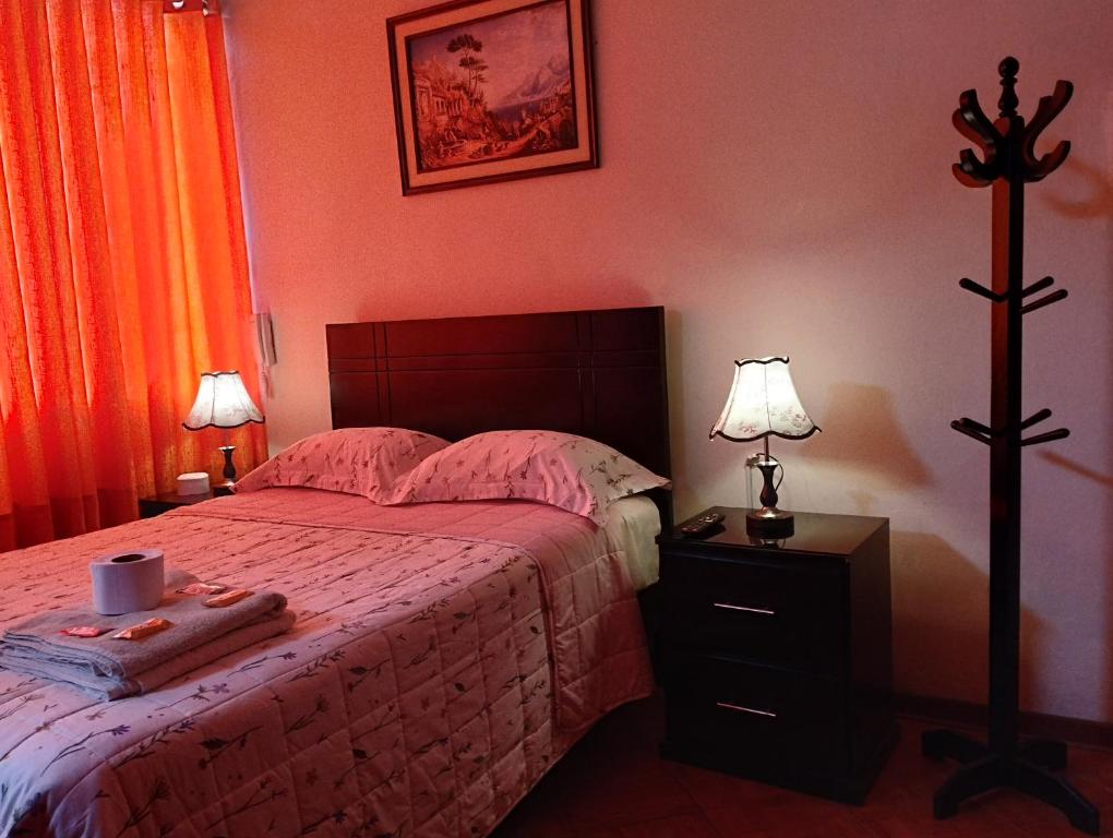 1 dormitorio con 1 cama y mesita de noche con 2 lámparas en Tambo Huascar, en Lima