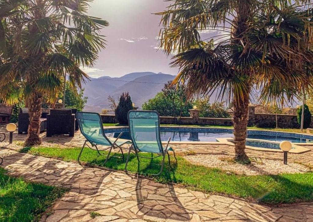 two chairs sitting next to a swimming pool with palm trees at Villa Exotic in Kavadarci