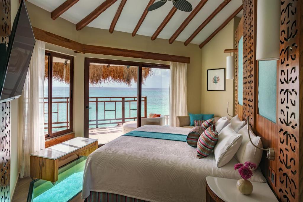 una camera con letto e vista sull'oceano di Palafitos Overwater Bungalows El Dorado Maroma - Adults Only a Playa del Carmen