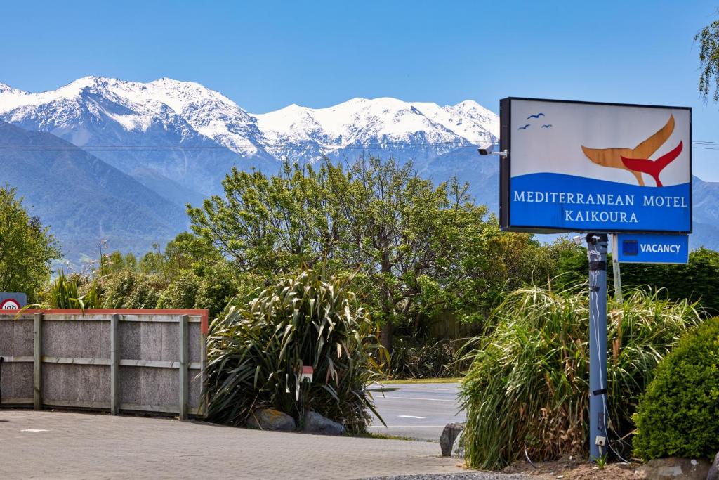 a sign for a hotel with mountains in the background at Mediterranean Motel Kaikoura in Kaikoura