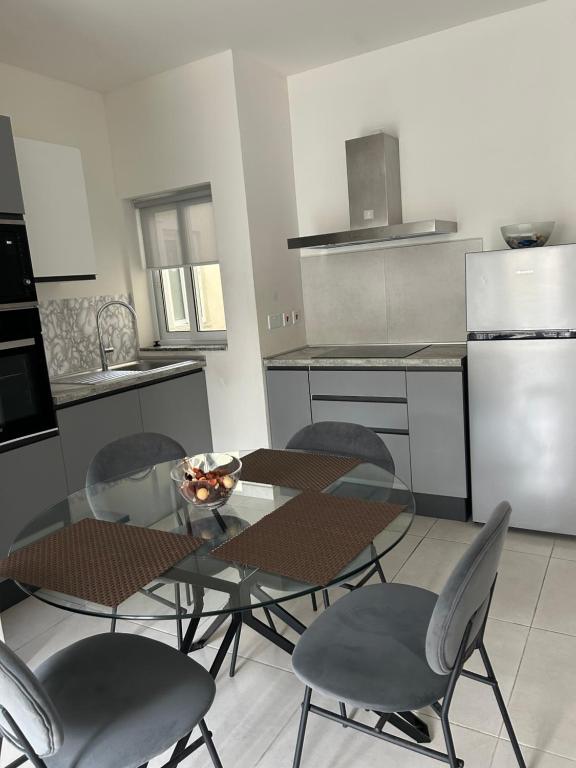 a kitchen with a glass table and chairs in it at Sunquest court in St Paul's Bay
