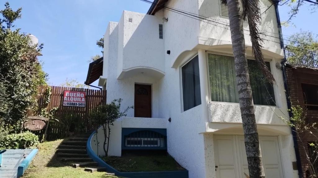a white house with a palm tree in front of it at El lugar in Villa Gesell