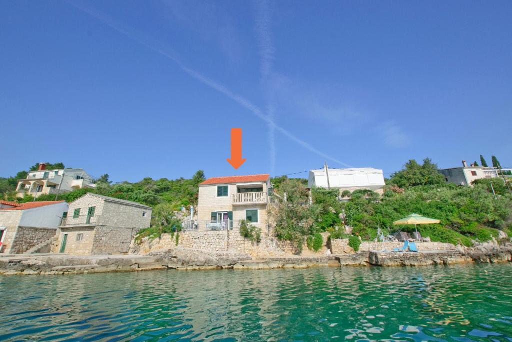a house on a hill next to a body of water at Apartment By the sea in Donje Selo na Šolti