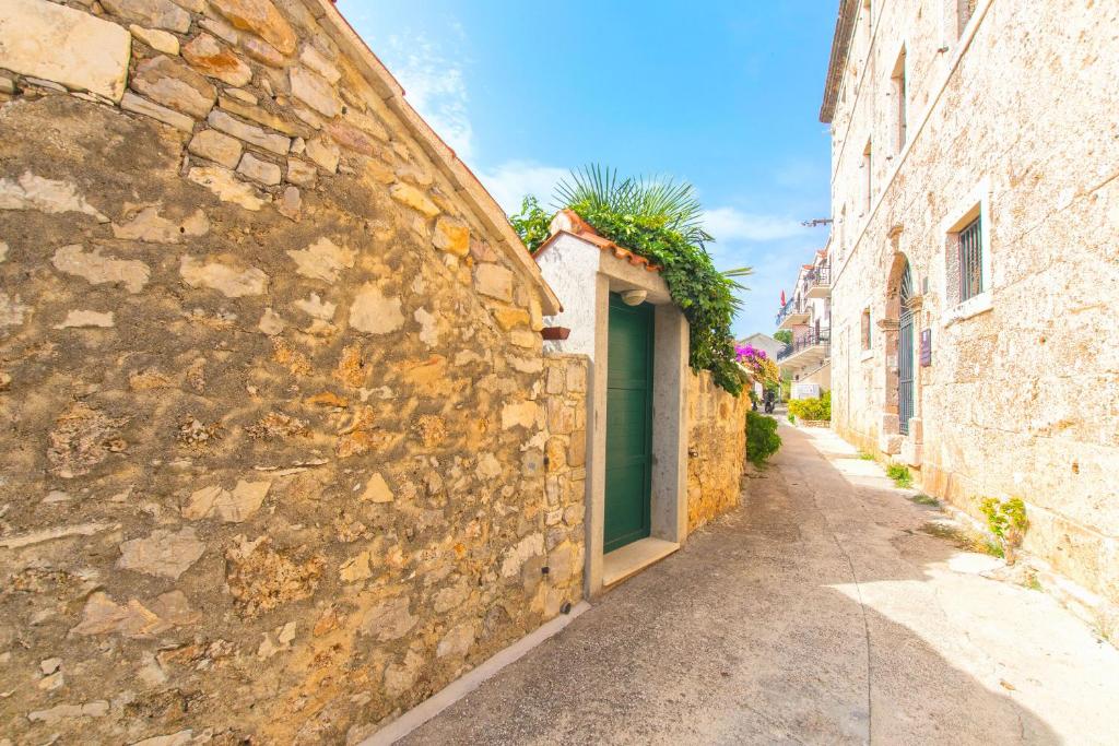 an alley in an old stone building with a green door at House Dinko in Bol