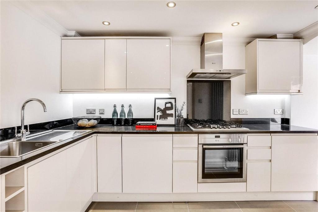 a kitchen with white cabinets and a sink at Mayfair Pied de Tier sleeps 6ppl in London
