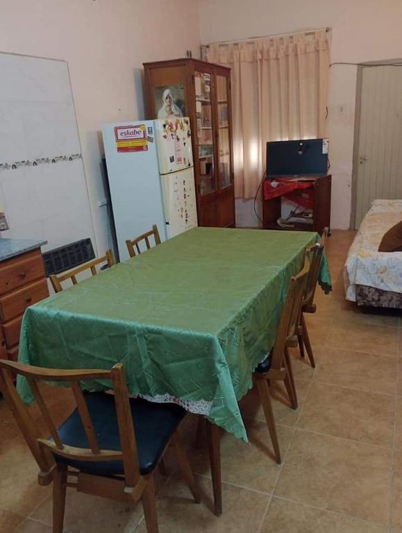 cocina con mesa verde con sillas y nevera en La cabaña en Mar de Ajó