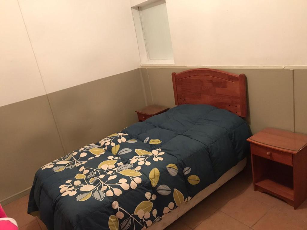 niewielka sypialnia z łóżkiem z niebieską kołdrą w obiekcie POSADA COPACABANA w mieście Tocopilla