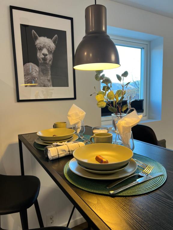 una mesa de comedor con platos amarillos y una lámpara en Stay Inn Bergen Apartment, en Bergen
