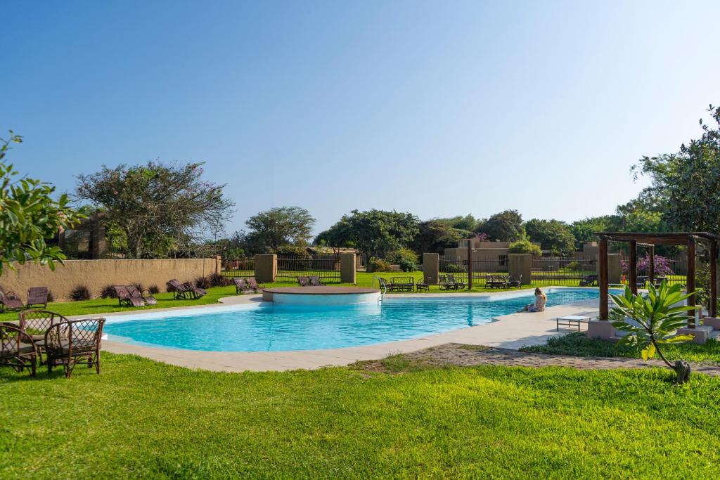 a large swimming pool in a park with green grass at DE SOL Y BARRO Moche Trujillo in Trujillo