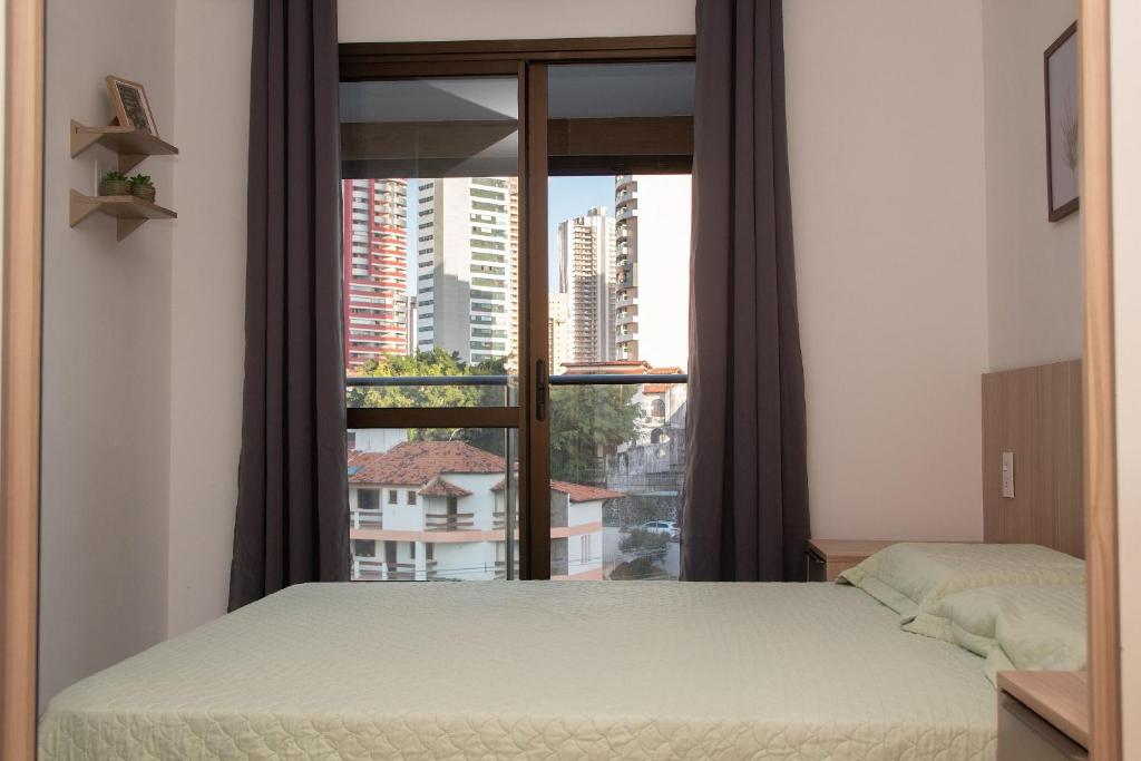 ein Schlafzimmer mit einem Bett und einem großen Fenster in der Unterkunft Salvador / Perto do Shopping Salvador e Shopping da Bahia / Caminho das Árvores in Salvador