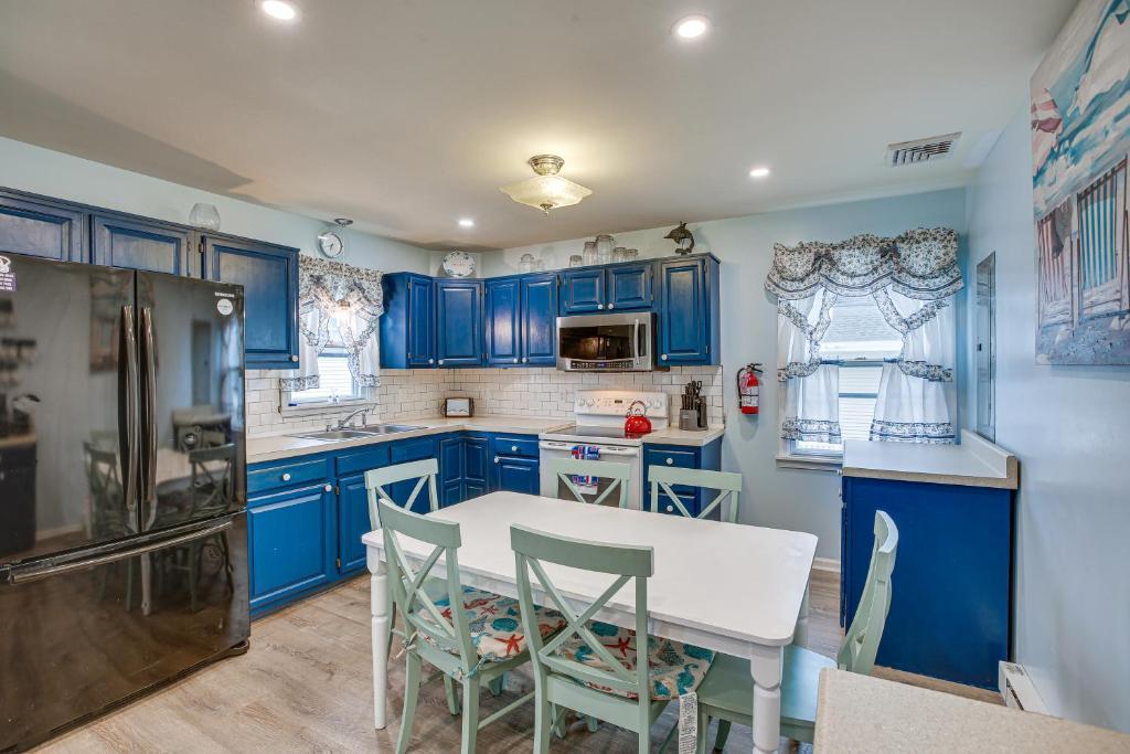 a kitchen with blue cabinets and a white table and chairs at Beach House with Private Pool in North Wildwood in North Wildwood