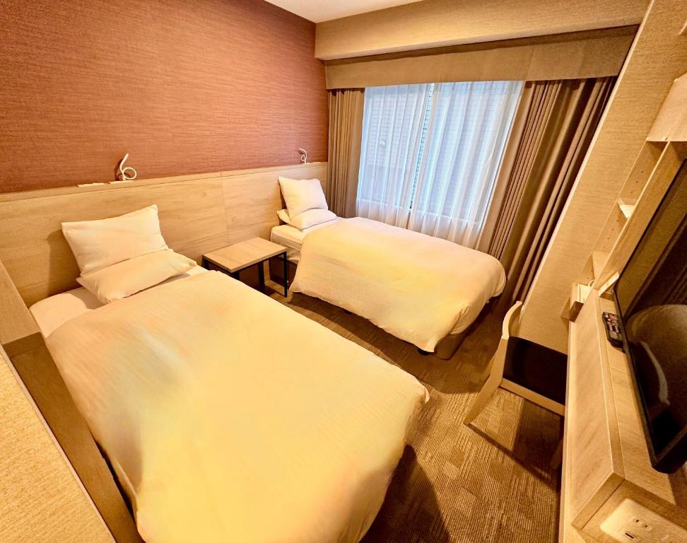 a hotel room with two beds and a window at Hotel Rose Garden Shinjuku in Tokyo