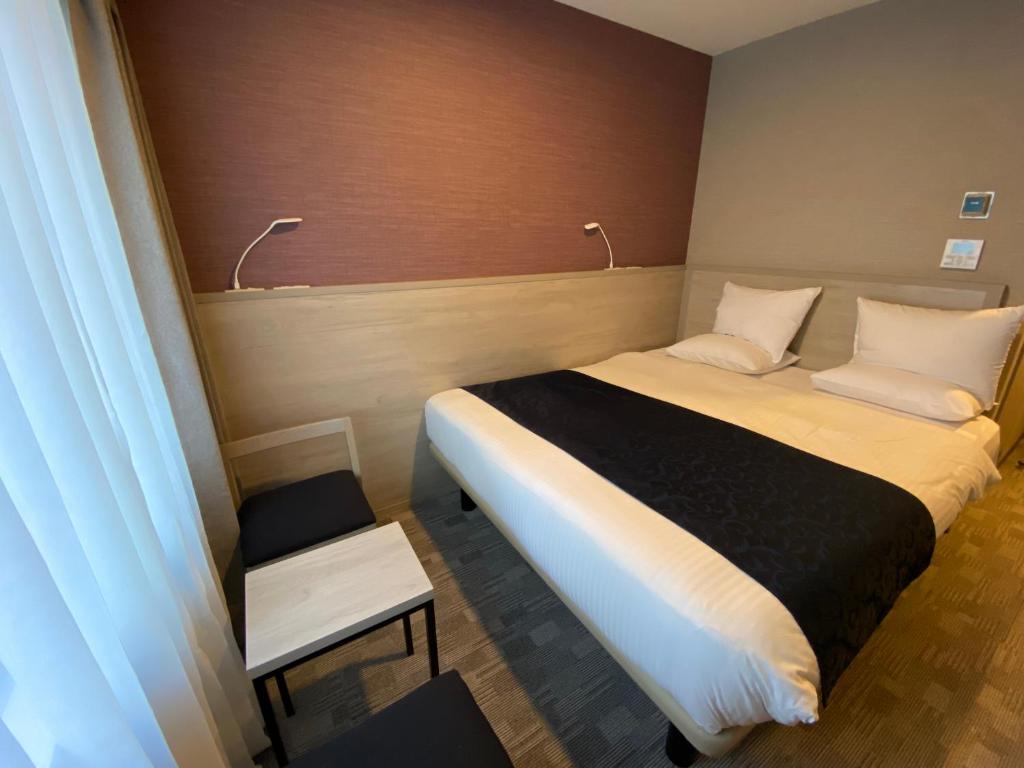 a small bedroom with a bed and a chair at Hotel Rose Garden Shinjuku in Tokyo