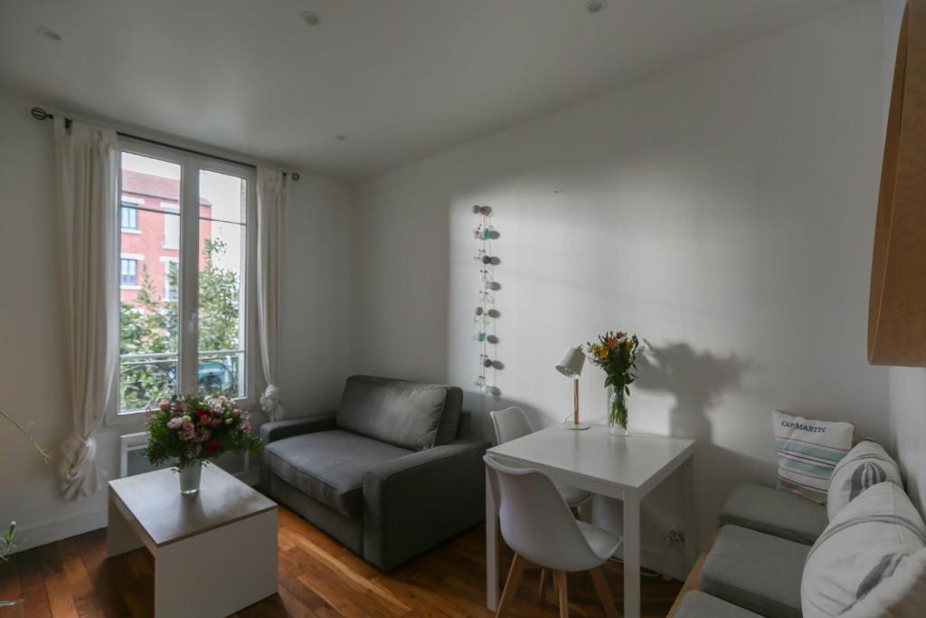 een woonkamer met een bank en een tafel bij Comfortable and well-appointed 30 m apartment in Vanves