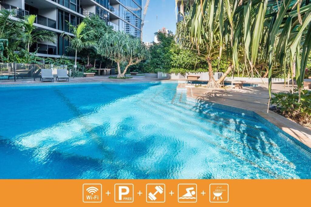une grande piscine bleue avec des palmiers et des bâtiments dans l'établissement Inner-city 1 bedroom Apartment Parking and Pool, à Brisbane