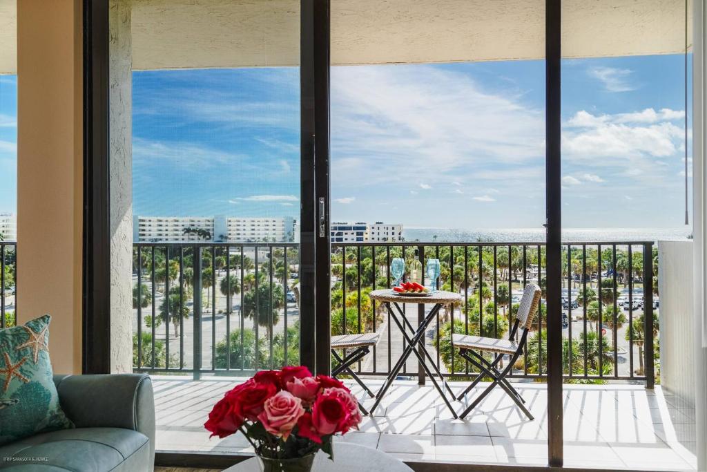 a living room with a balcony with a table and roses at Our House At The Beach, East Tower, 5th Fl in Siesta Key