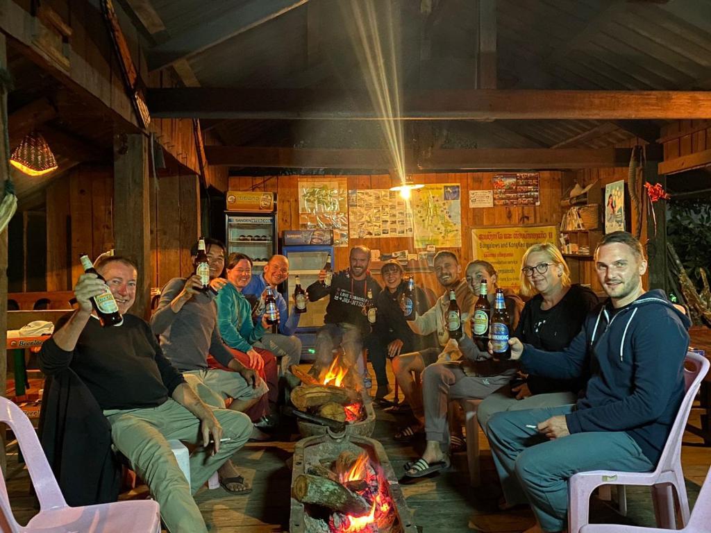 a group of people sitting around a fire at Kongkeo Guesthouse in Muang Ph&ocirc;nsavan