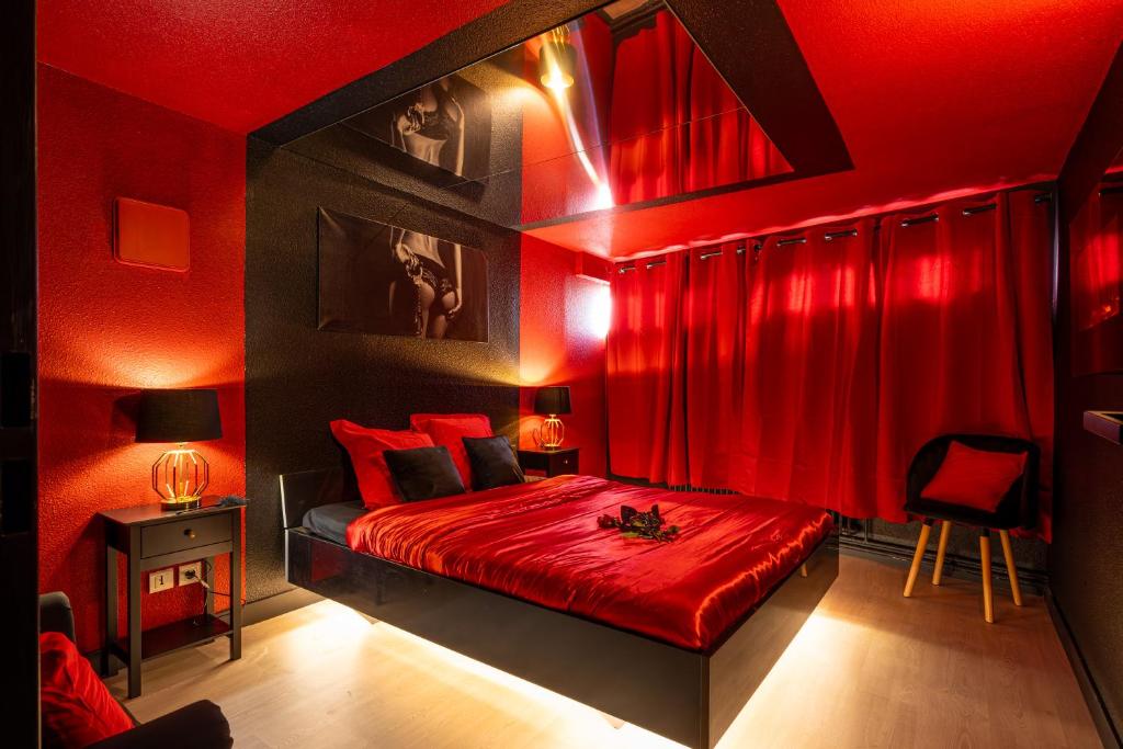 a red bedroom with a bed with red curtains at Cocon Sensuel - 50 Nuances - Les Cocons de Nath in Montbéliard