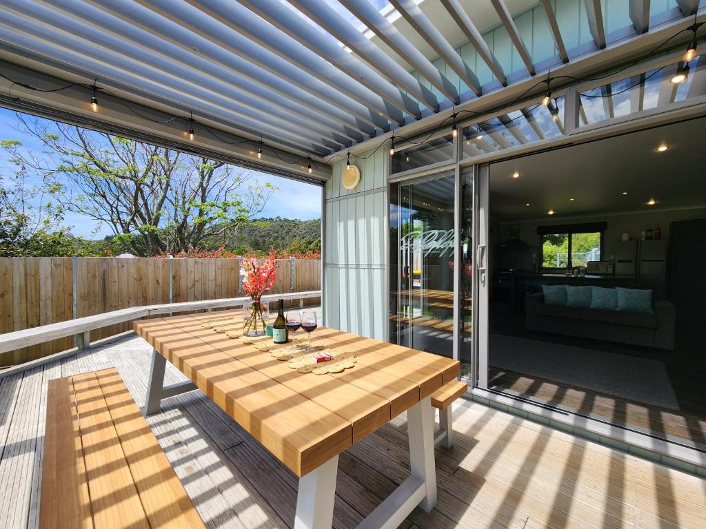 eine Terrasse mit einem Holztisch auf einer Terrasse in der Unterkunft The perfect Hahei bach - Dulop in Hahei
