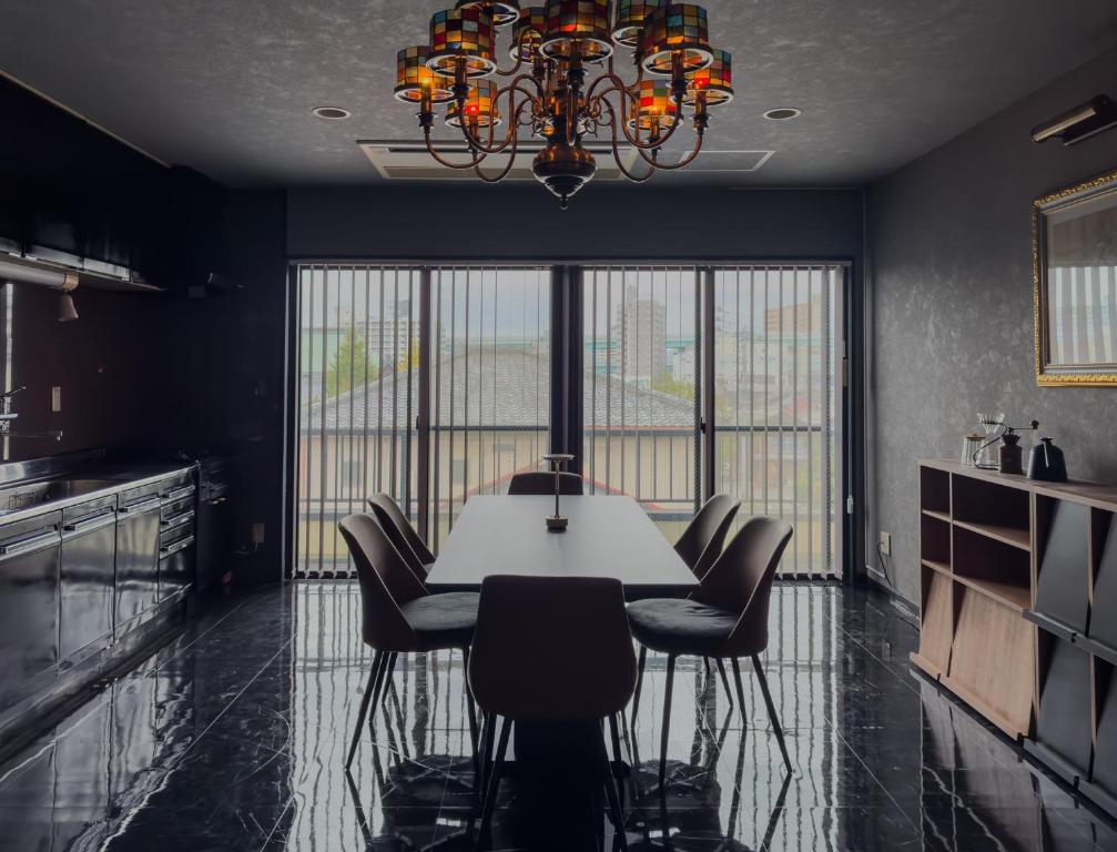 a dining room with a table and chairs and a chandelier at AMP FLAT Ogokusou in Fukuoka