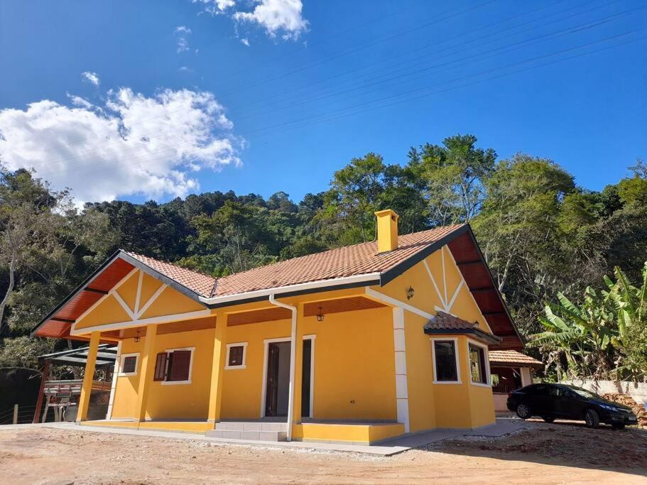 una casa gialla con una macchina parcheggiata di fronte di Seu Refúgio na Montanha Magnífica a Santo Antônio do Pinhal