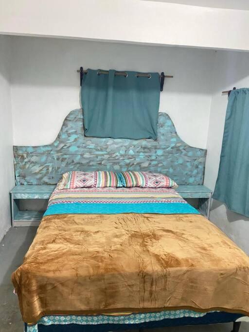 Schlafzimmer mit einem Bett mit blauem Kopfteil in der Unterkunft Low Key Apartment in Punta Blanca