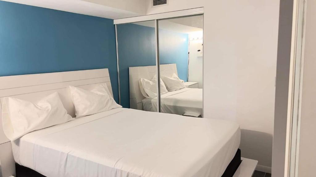 een slaapkamer met een wit bed en een spiegel bij A lovely - 1 bedroom condo with swimming pool in Toronto