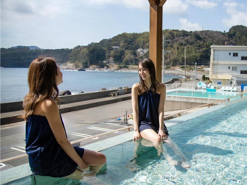 dos mujeres sentadas en el agua en una piscina en 自家源泉の宿 竜宮の使い Ryugu no Tsukai, en Higashiizu