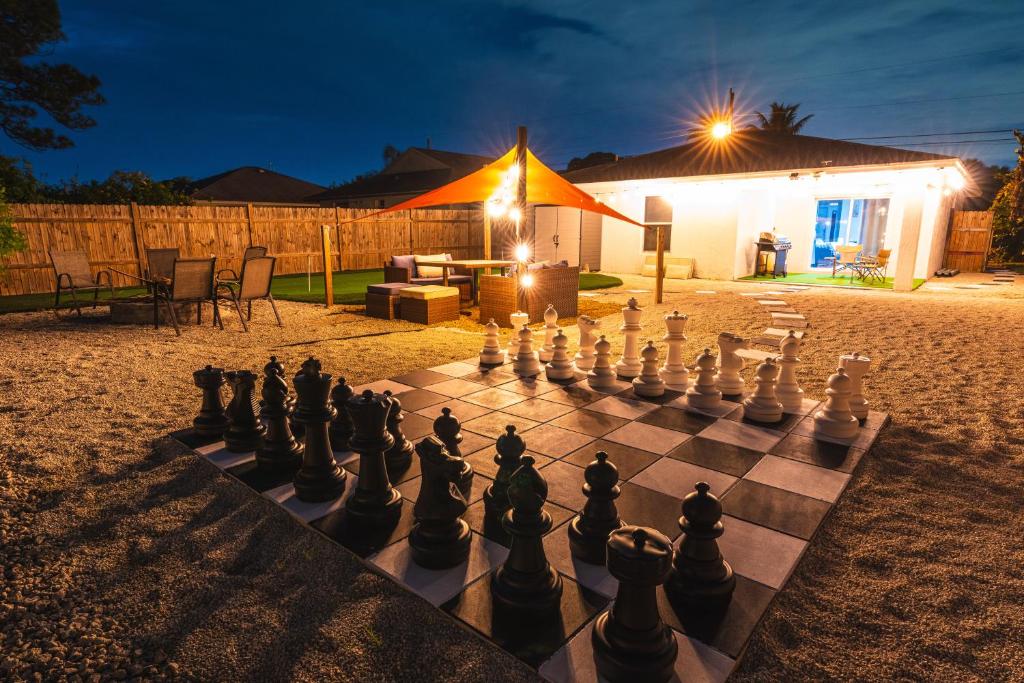 um tabuleiro de xadrez no quintal de uma casa à noite em Golfers Paradise 4-hole PUTT-PUTT, Mega Chess with huge backyard, hammock em Jupiter