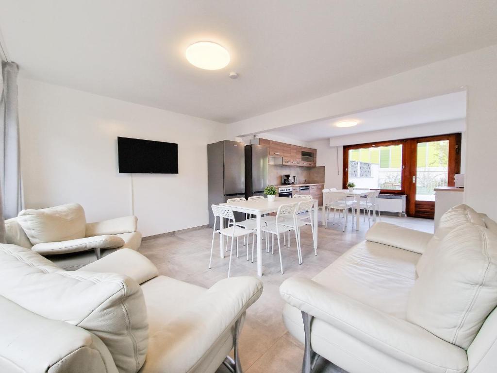 een woonkamer met witte meubels en een keuken bij RAJ Living - 6 Room House with Terrace and Parking - 25 Min Messe DUS & Airport DUS in Duisburg