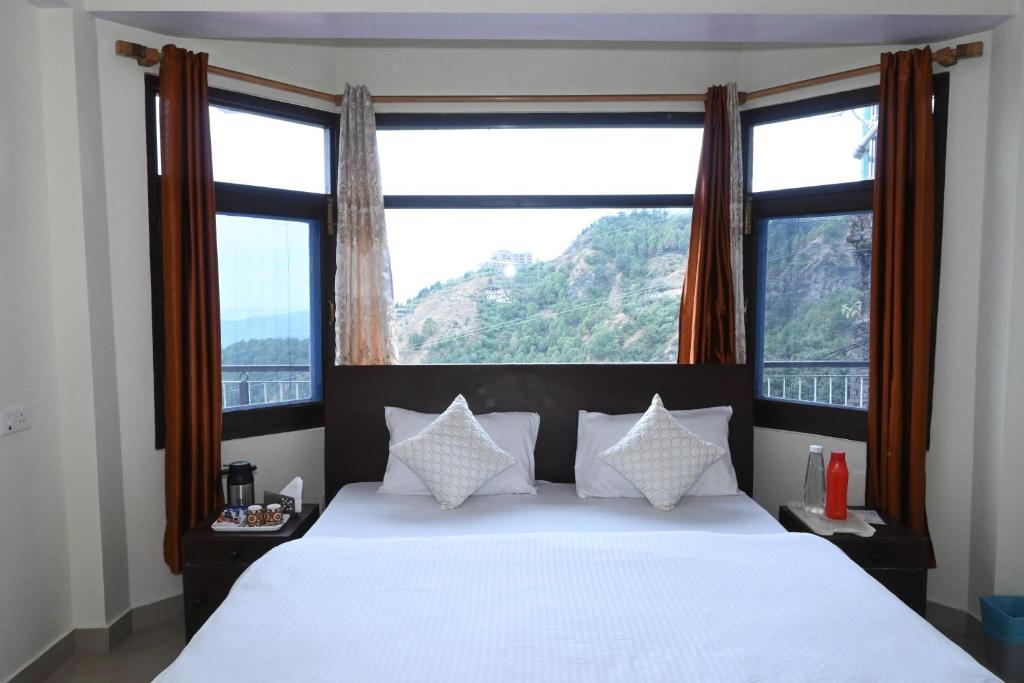 een slaapkamer met een wit bed en een groot raam bij Om Niwas Homestay in Shimla