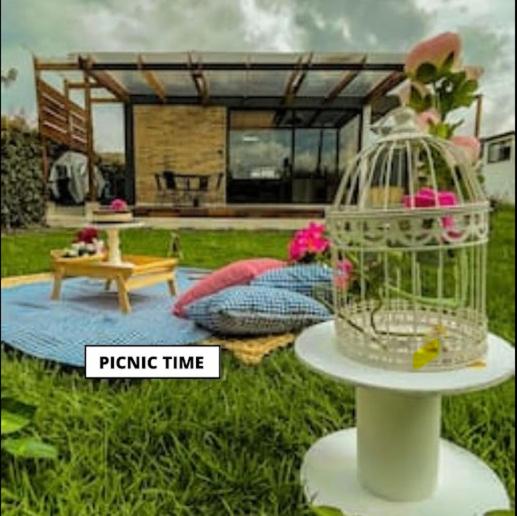 a bird cage on a stand in front of a house at Carmesí Smart Glamping in Simijaca