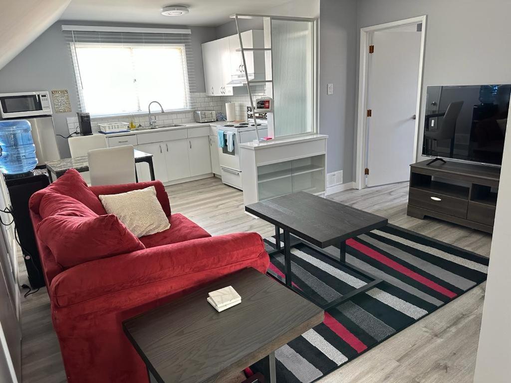 a living room with a red couch and a kitchen at Spotless 2 Bedrooms Suite 2 in Winnipeg in Winnipeg
