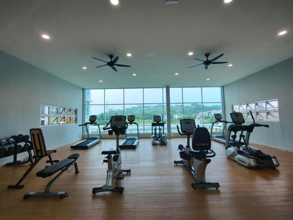 um ginásio com passadeiras e equipamento de exercício numa sala com janelas em Kuantan Homestay by WyattHomes em Kuantan