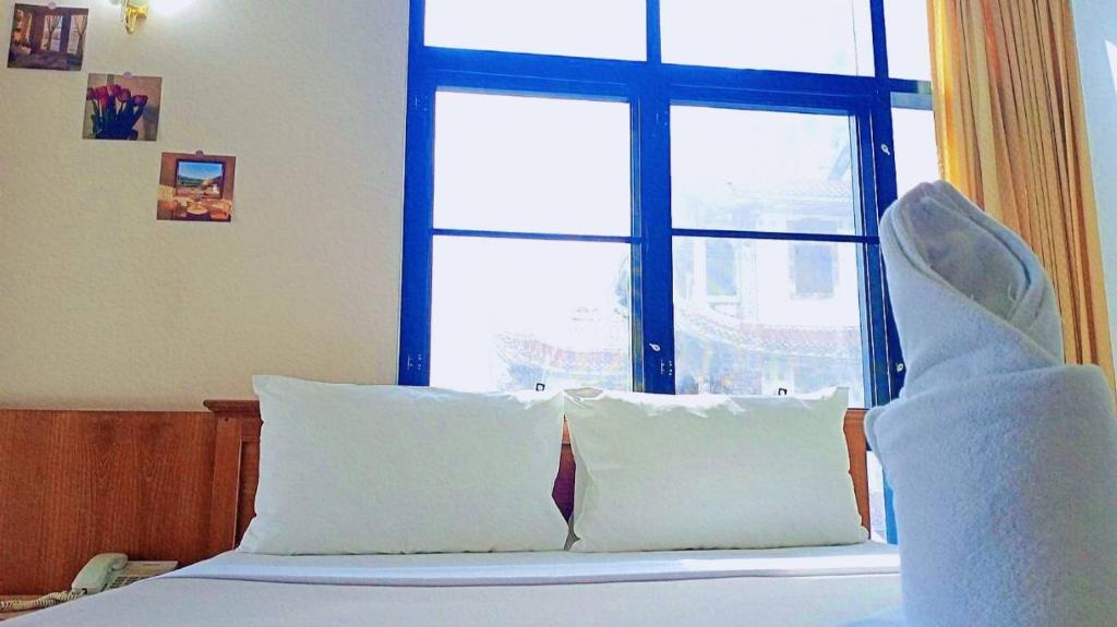 a bedroom with a bed with white pillows and a window at Wantana Mansion in Hat Yai